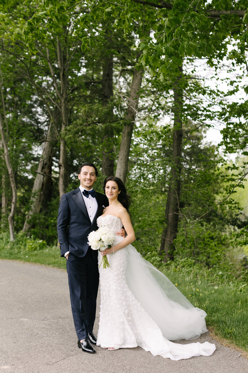 Bride and groom standing together on a green estate path